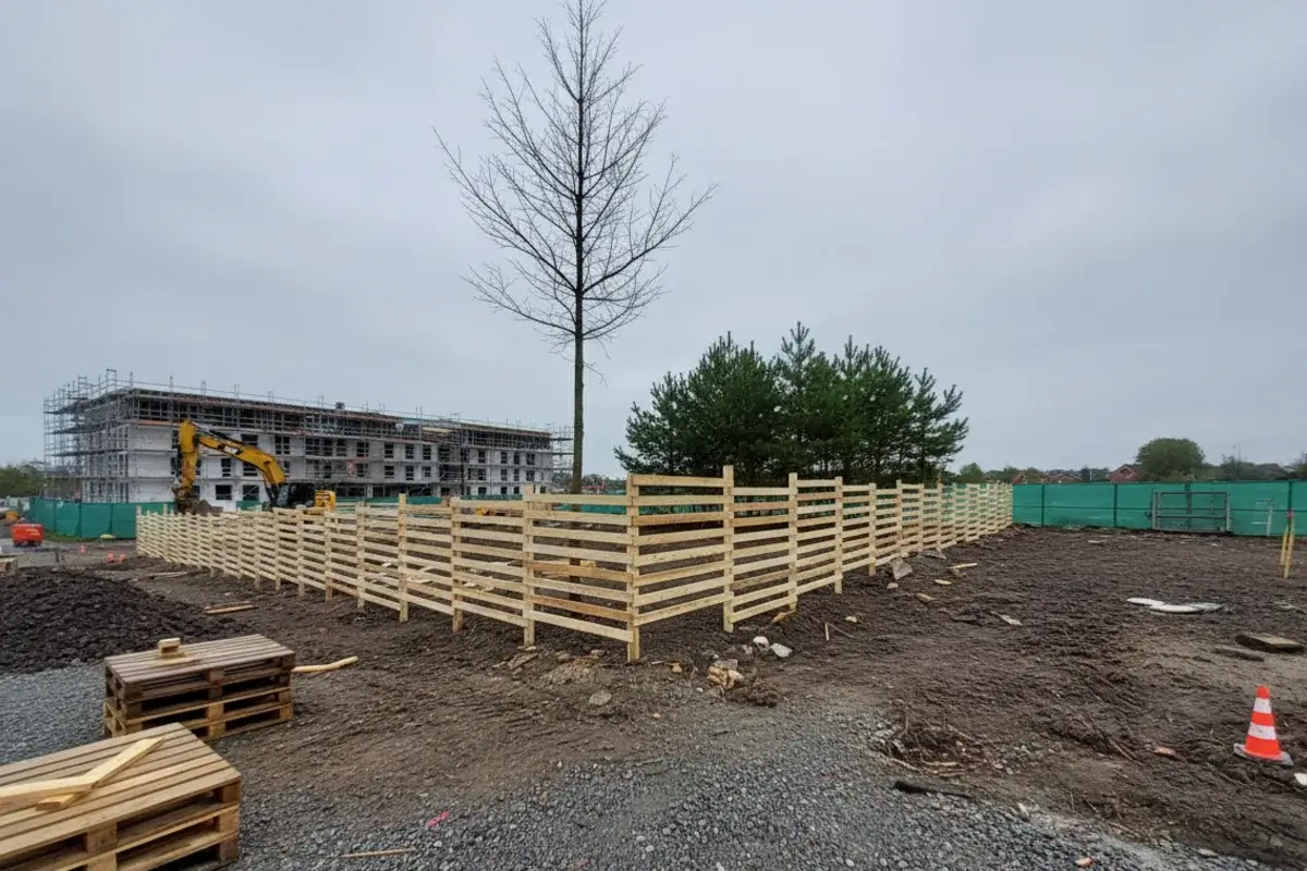 Ein stabiler Baumschutzzaun aus Holz, der nach DIN 18920 auf einer Baustelle in München zum Schutz von Bäumen errichtet wurde.